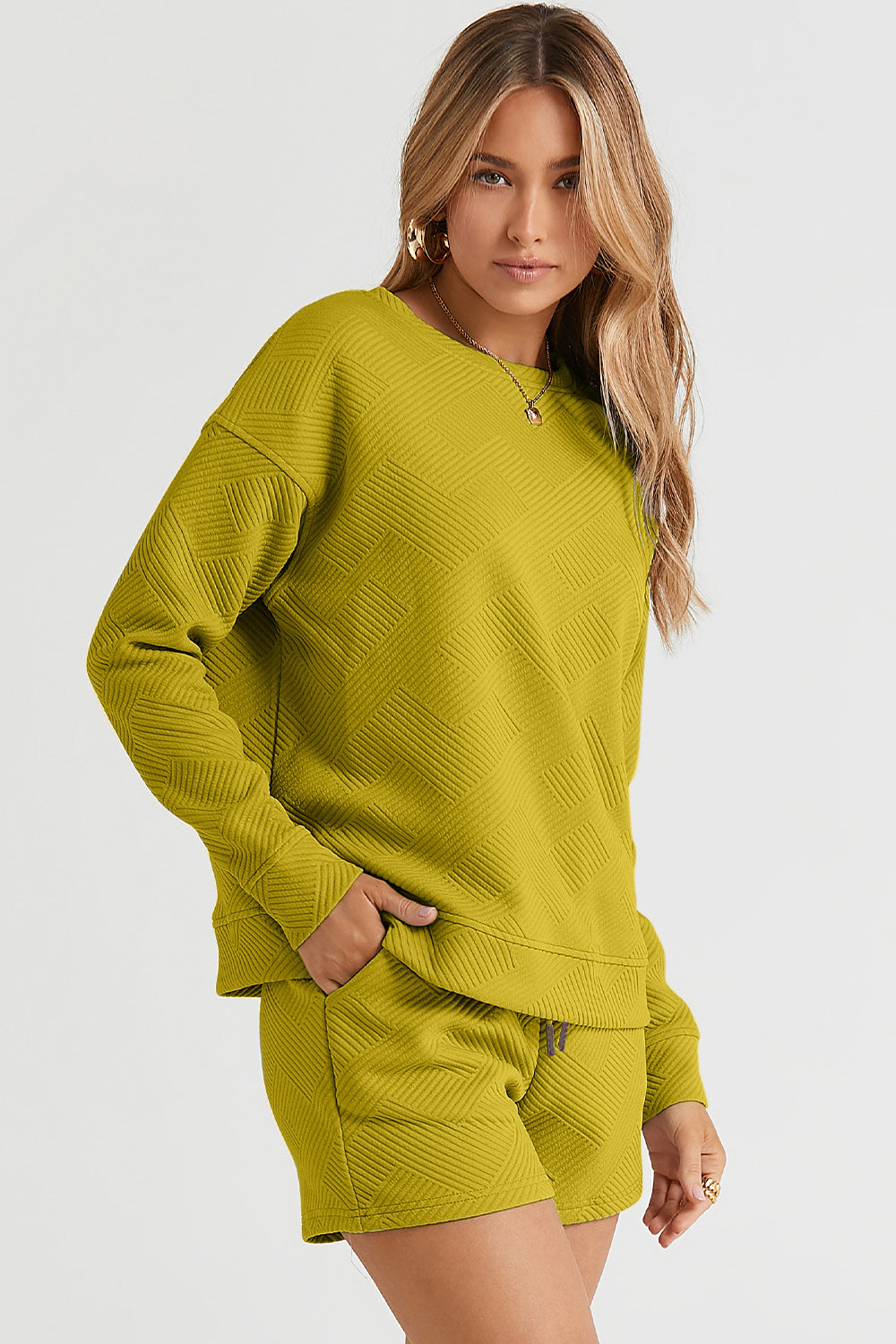 Woman wearing olive green textured long sleeve top and drawstring shorts set with pockets, made of polyester and spandex blend.