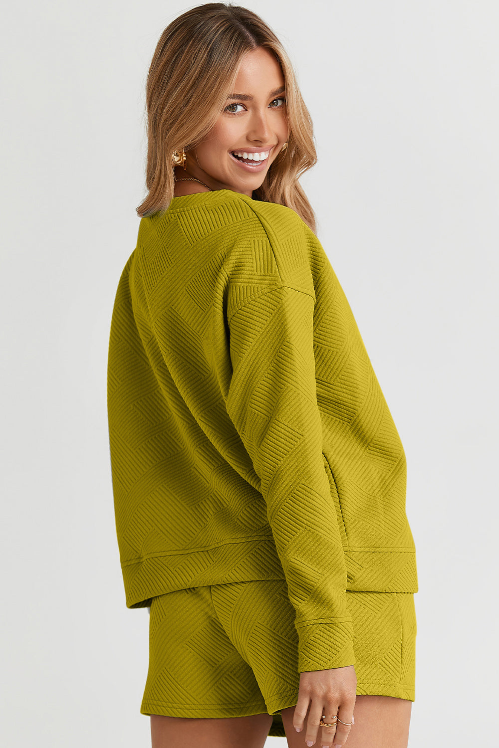 Woman wearing a green texture long sleeve top and drawstring shorts set, featuring pockets and slightly stretchy polyester-spandex material.