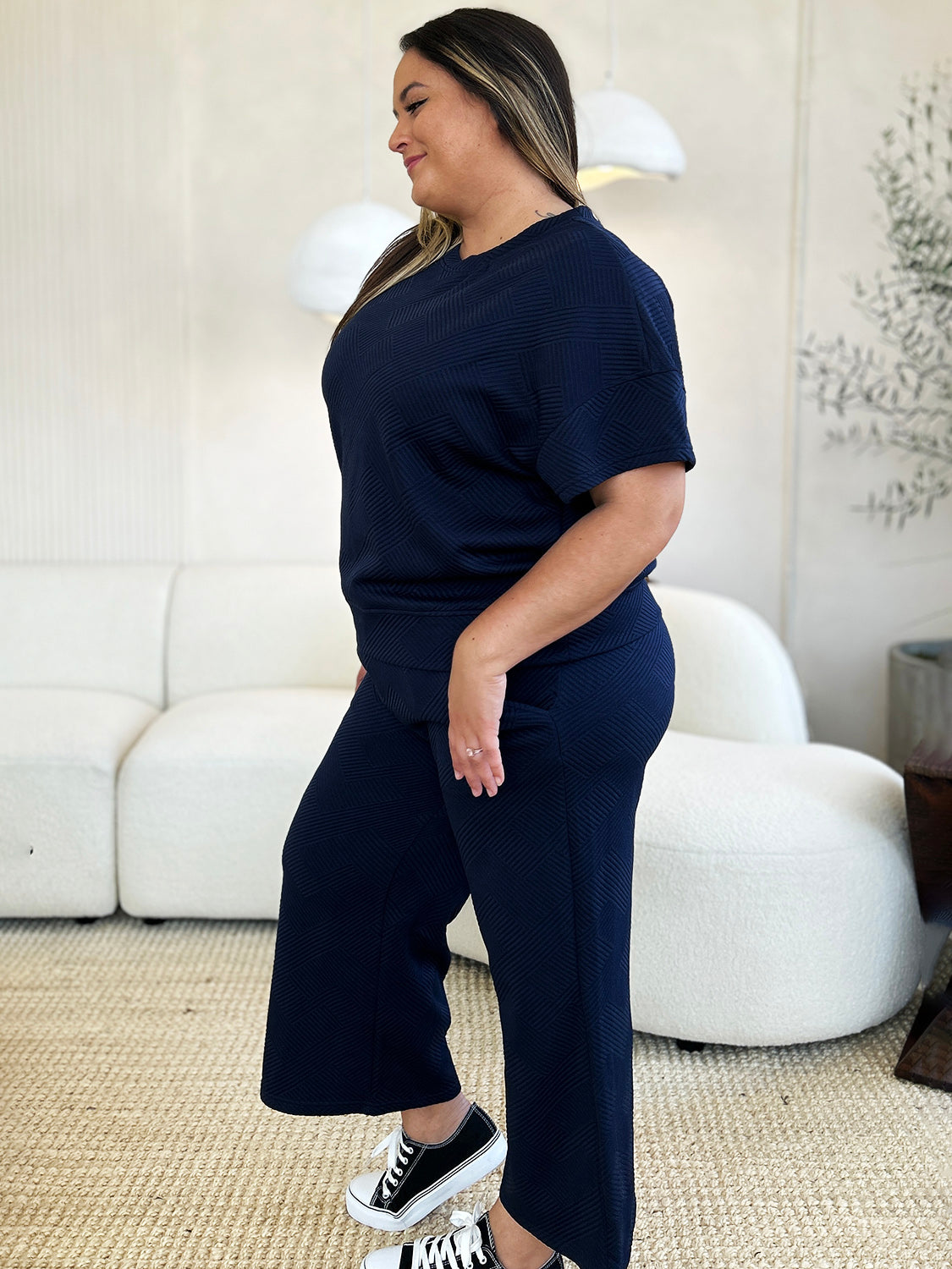 Woman wearing navy blue two-piece outfit with short sleeve top and pants, featuring a slightly stretchy fabric for comfort.