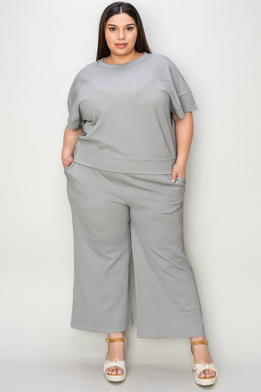 Woman wearing gray short sleeve top and pants set with drawstring, slightly stretchy fabric, composed of 95% polyester, 5% spandex.