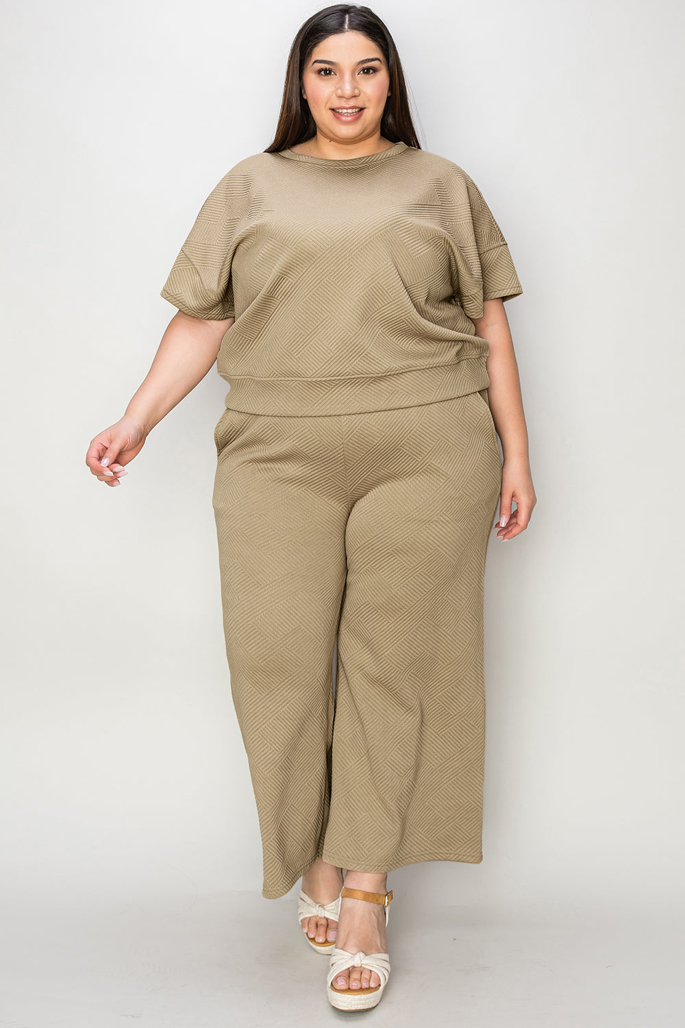 Plus-size model wearing beige short sleeve top and pants set with drawstring waist, made from slightly stretchy polyester spandex blend.