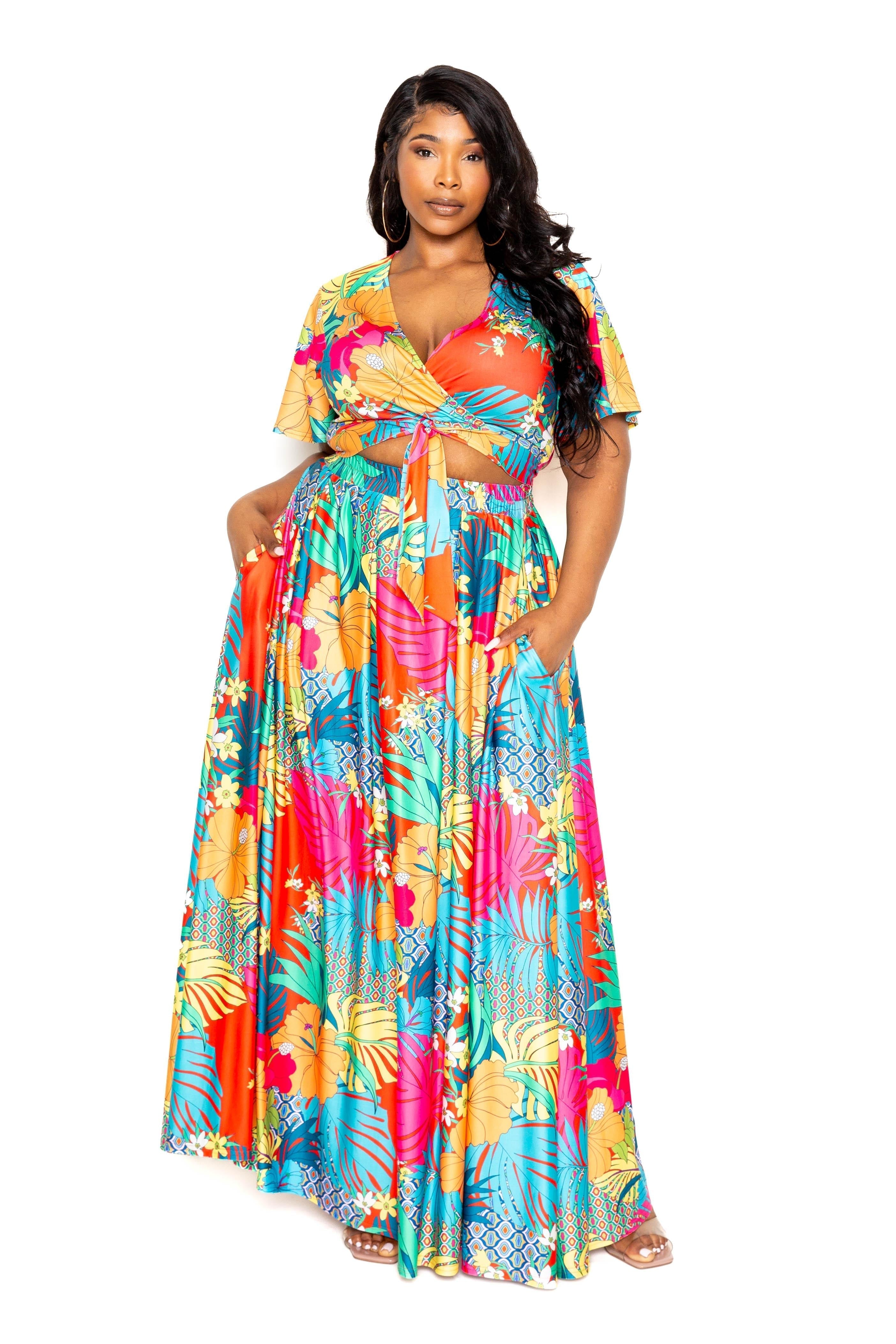 Plus size woman wearing tropical floral maxi skirt and top set in vivid colors, polyester-spandex blend, sizes 1XL to 3XL.