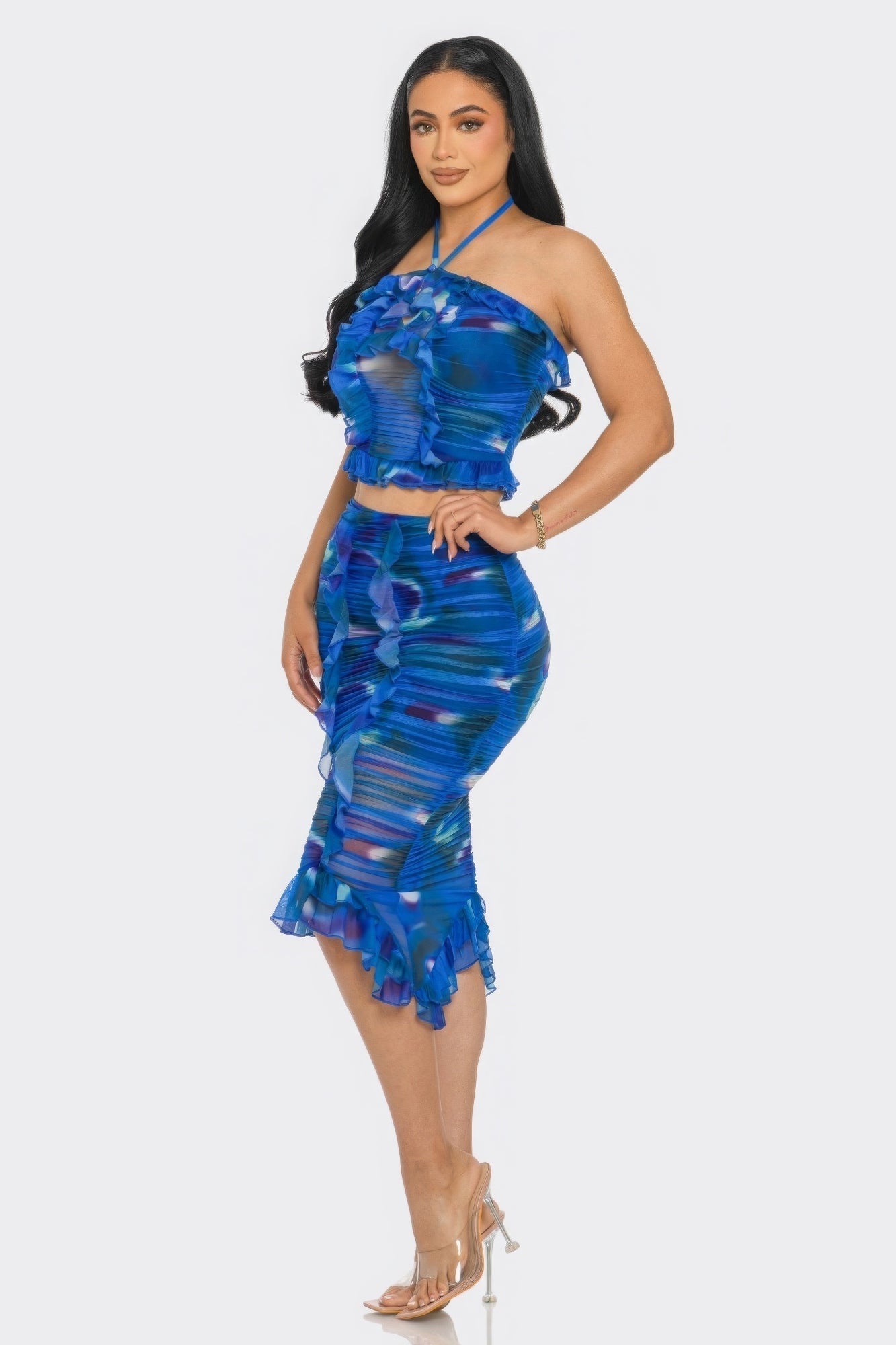 Woman wearing vibrant blue tropical print mesh ruffle halter skirt set with ruched detailing and playful ruffle trim.