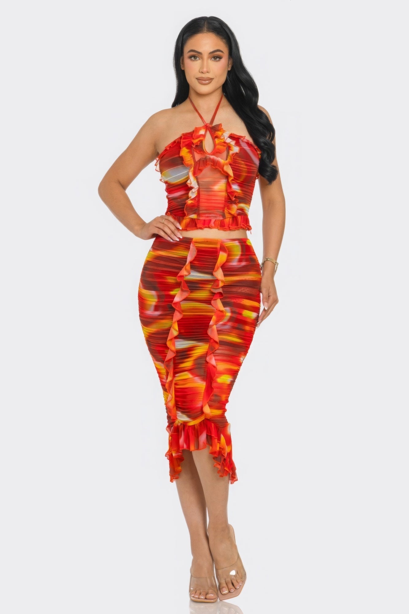 Woman wearing vibrant orange tropical waters print mesh ruffle halter skirt set with ruched detailing and a ruffle-trimmed skirt.