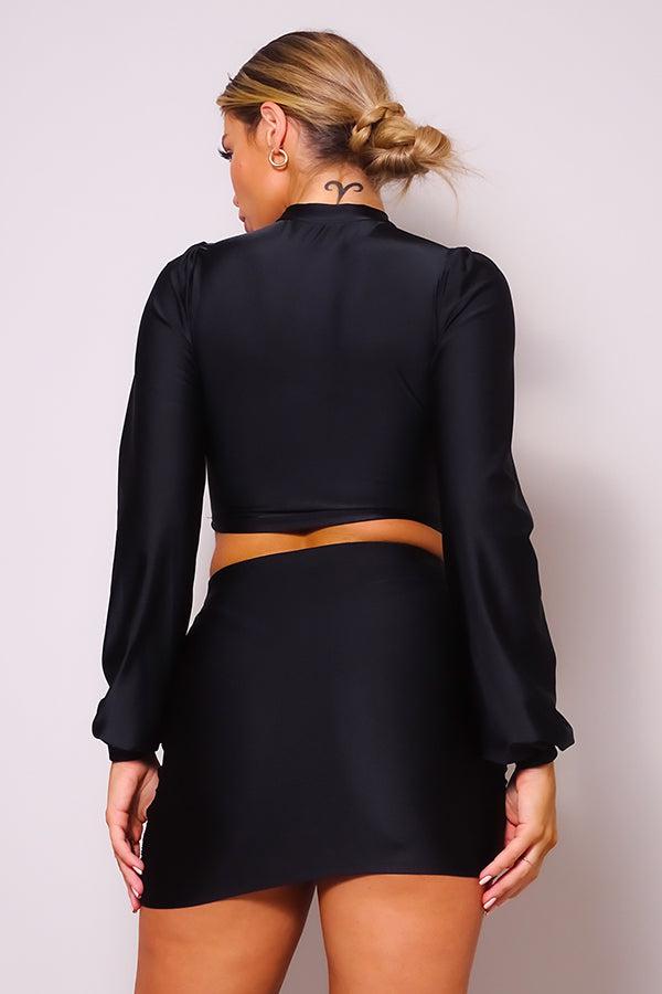 Woman wearing black turtleneck blouse and side ruched mini skirt set, showcasing back details and elegant fit.