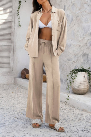 Woman wearing beige knit matching set with button-up cardigan and wide-leg pants, white bikini top underneath, standing on white tile floor with pl...