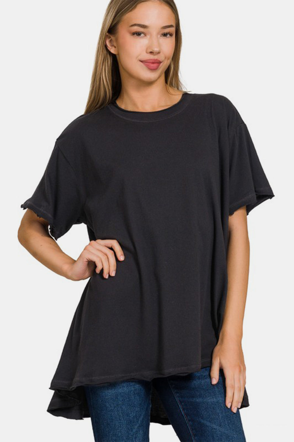 Woman wearing a black round neck short sleeve t-shirt with a high-low hem, made of 100% cotton and slightly stretchy material.