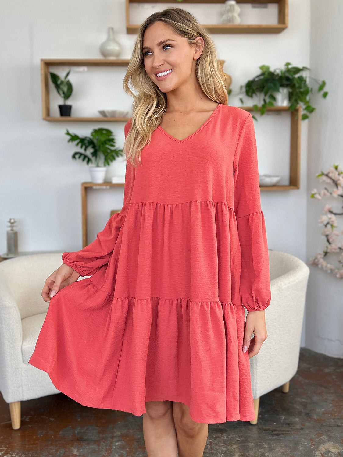 Woman wearing V-Neck Balloon Sleeve Tiered Dress with Pockets in coral, showcasing stylish, pocketed, ruffled design.