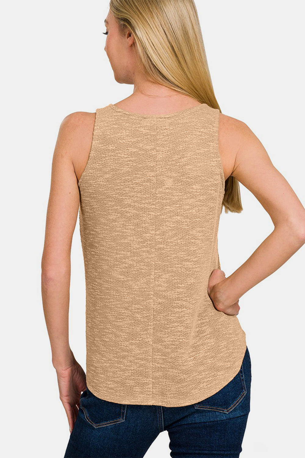 Woman wearing a V-Neck Curved Hem Tank in beige, showcasing the versatile back view with curved hem paired with jeans.