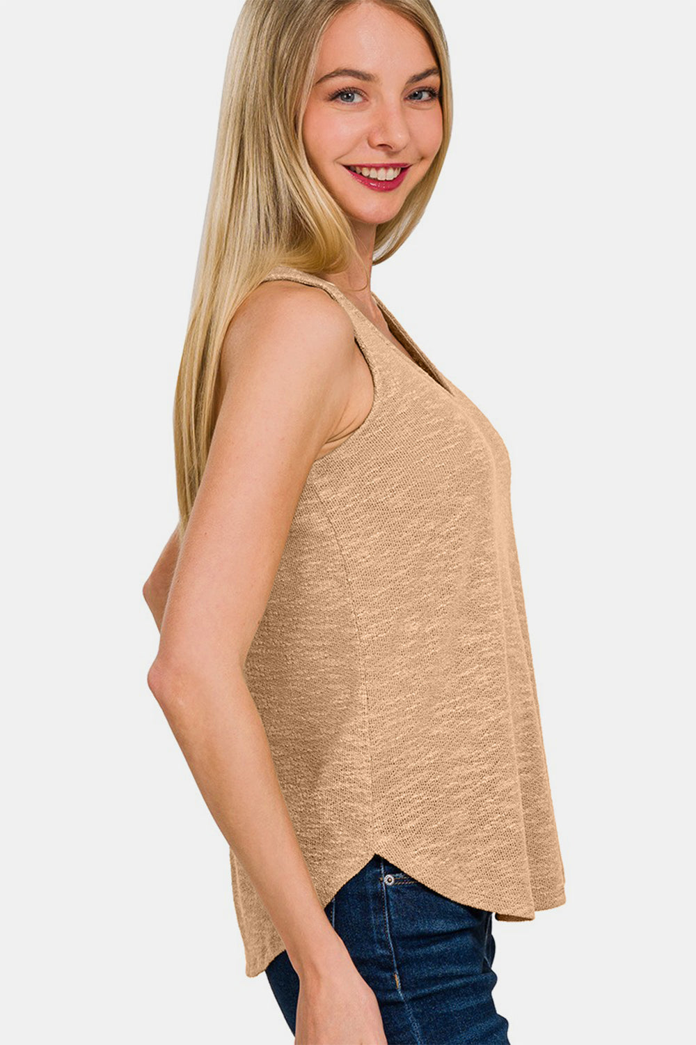 Woman wearing beige V-Neck Curved Hem Tank with jeans, showcasing a flattering silhouette and feminine curved hem.