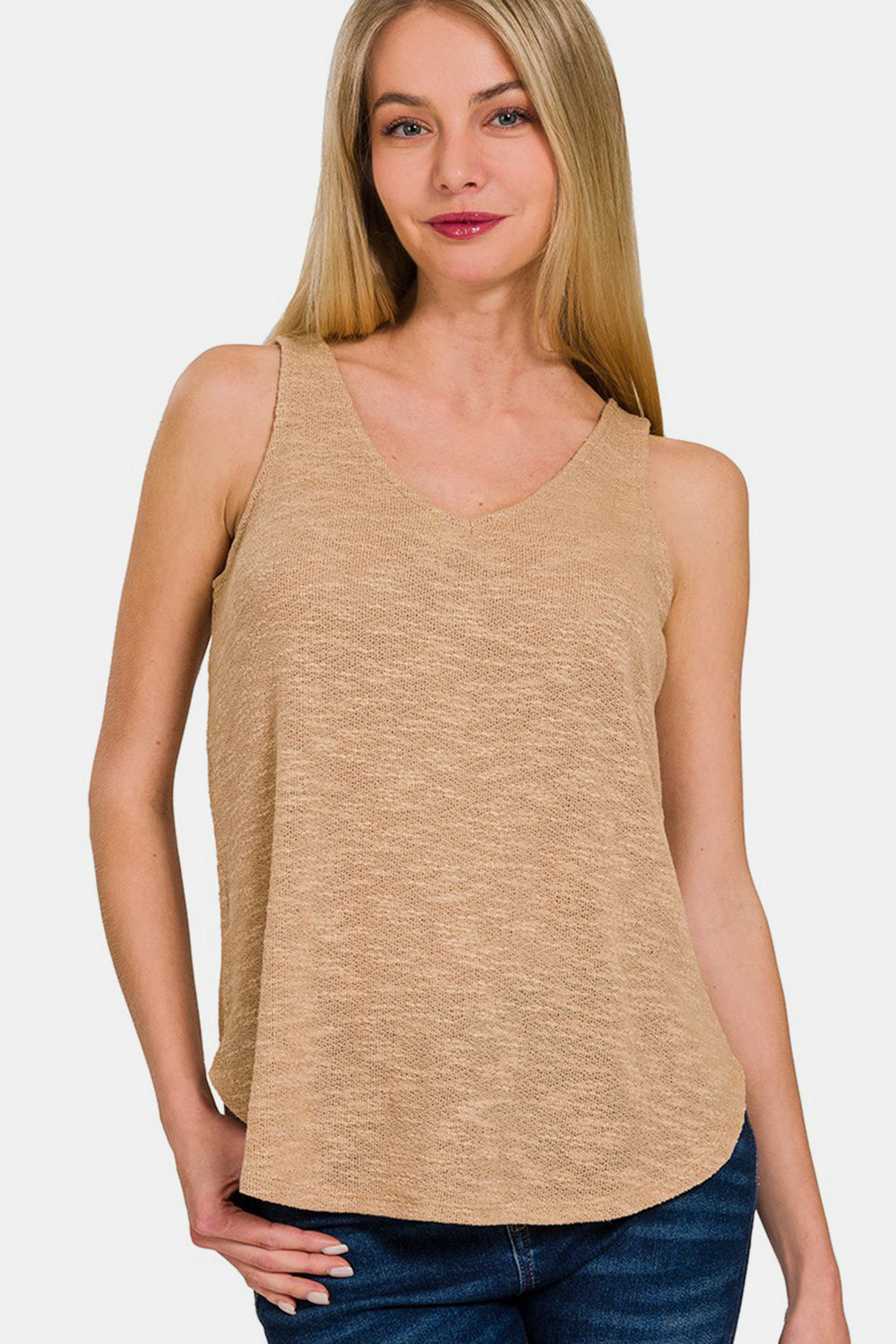 Woman wearing a beige V-Neck Curved Hem Tank, featuring a flattering silhouette and soft fabric, paired with blue jeans for a casual look.