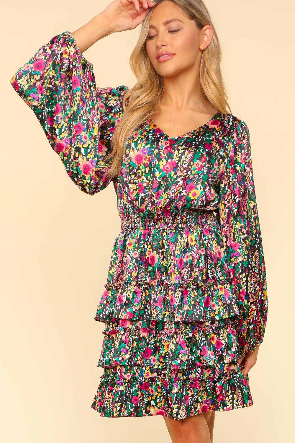 Woman wearing a V-Neck Satin Floral Layered Dress with ruffled sleeves, smocked waist, and vibrant floral print.