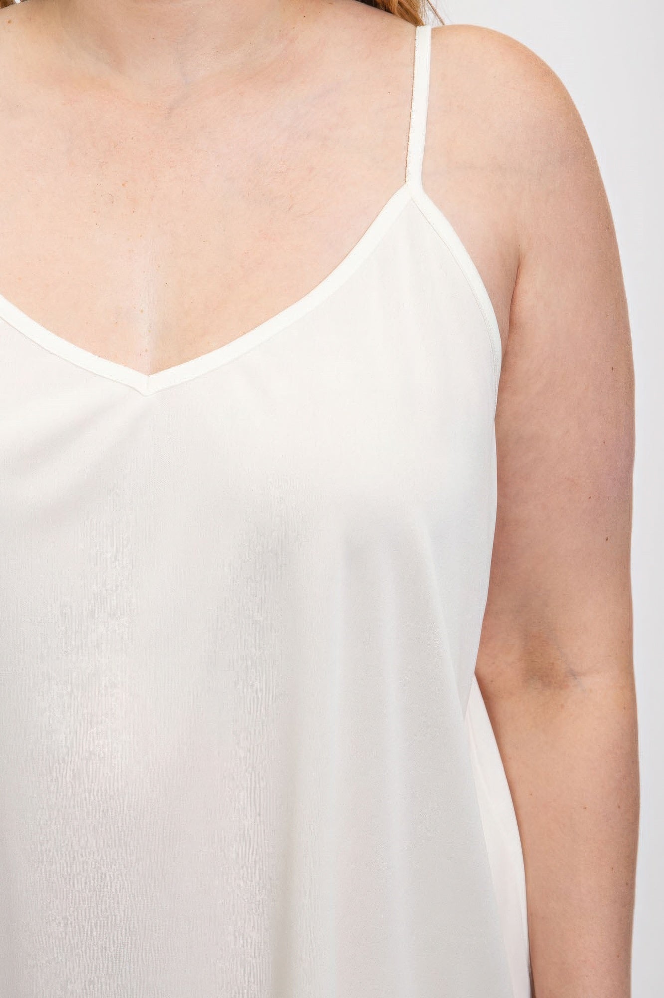 White V-neck slip dress with adjustable straps in smooth polyester fabric for a sleek and comfortable fit.