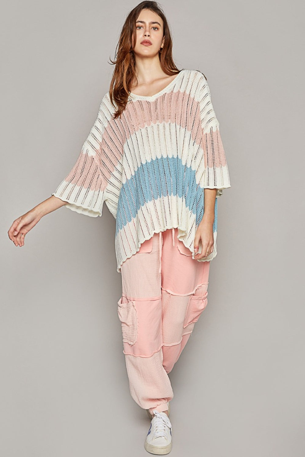 Woman wearing oversized striped weave sweater and pink pants, showcasing a casual, comfortable fashion style.