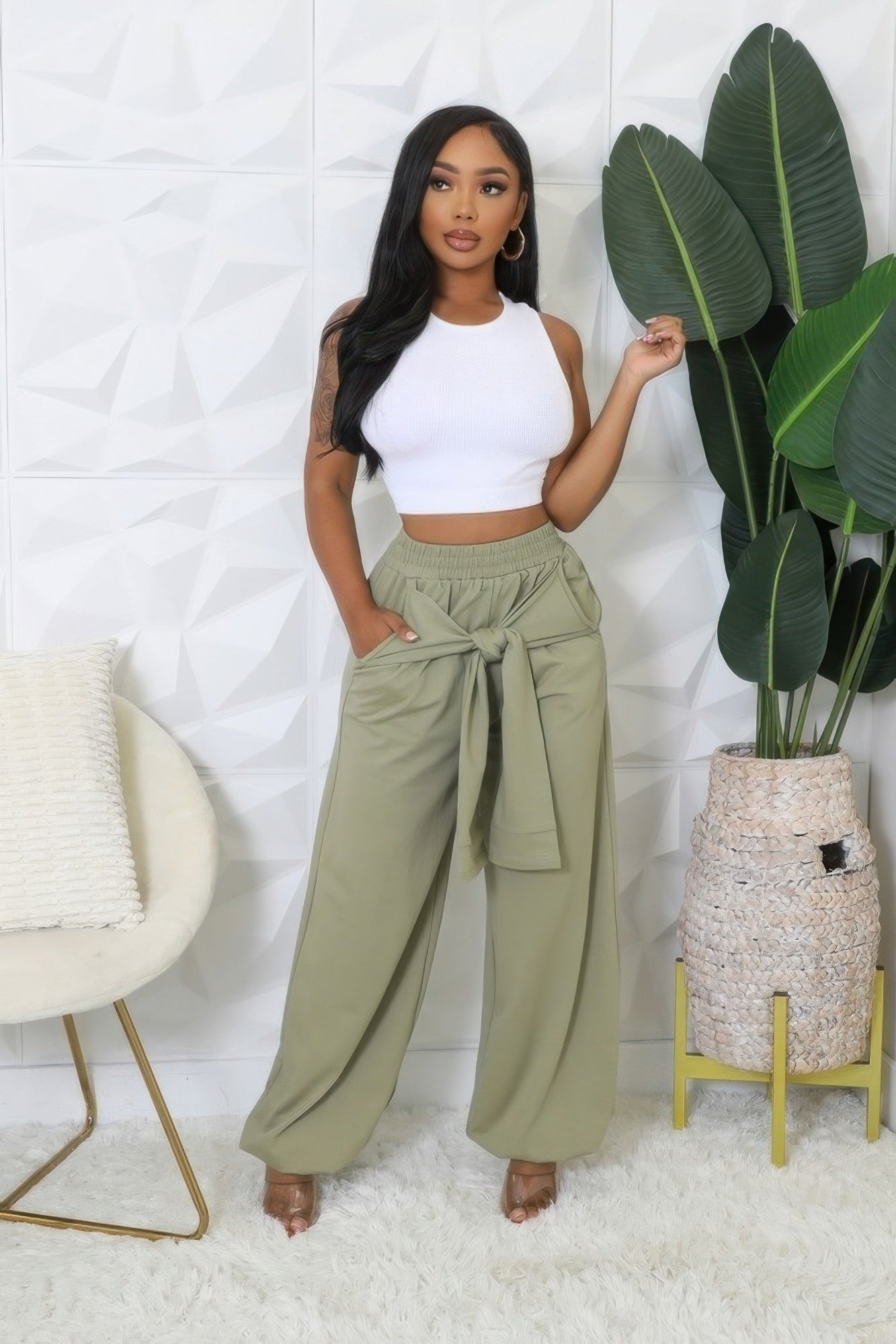 Woman wearing high-waisted stretch pants with elastic waistband and cuffed bottoms, styled with a white top in a modern setting.