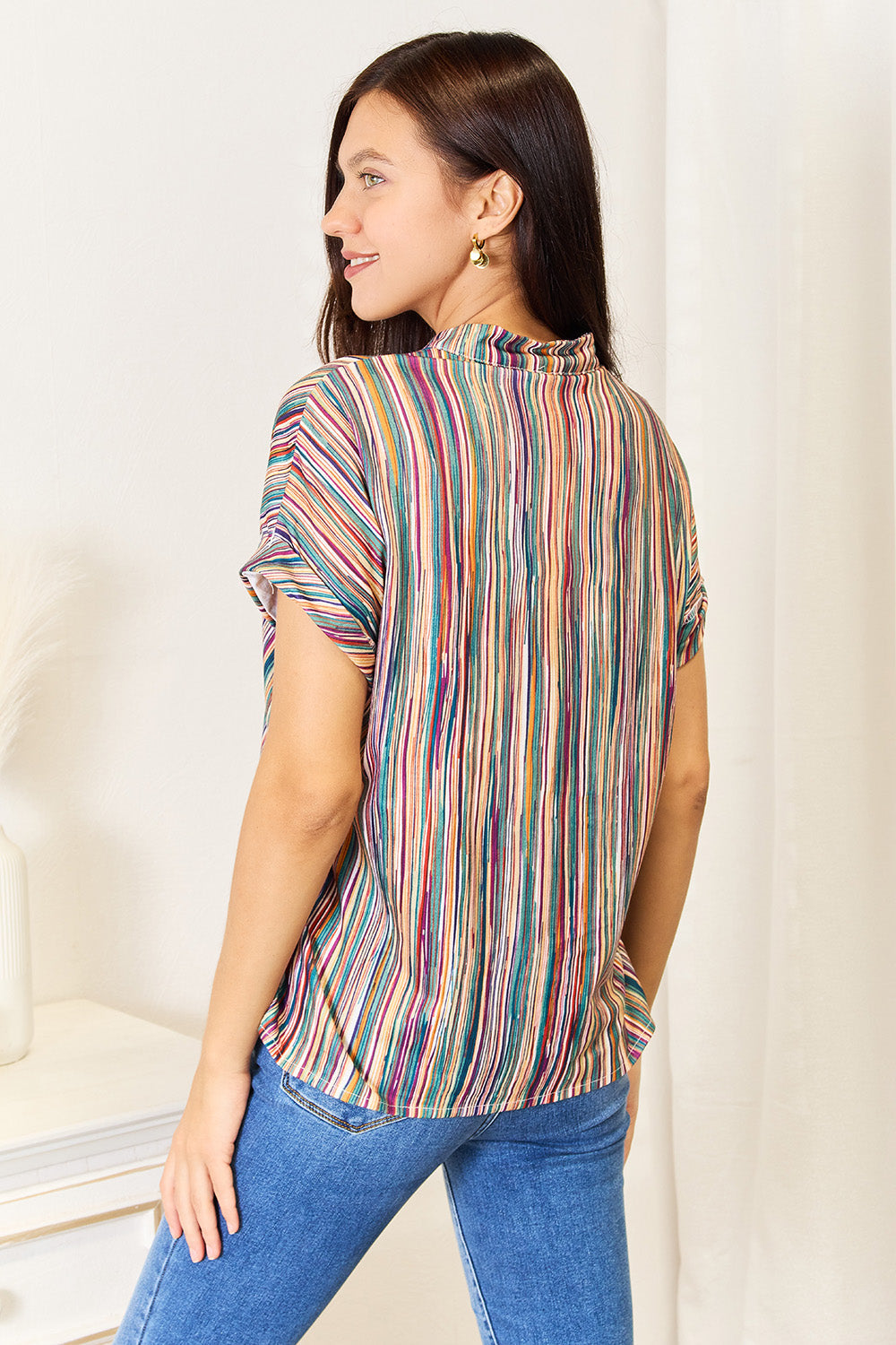 Woman wearing multicolored stripe notched neck top with decorative buttons, showcasing a stylish and versatile design.