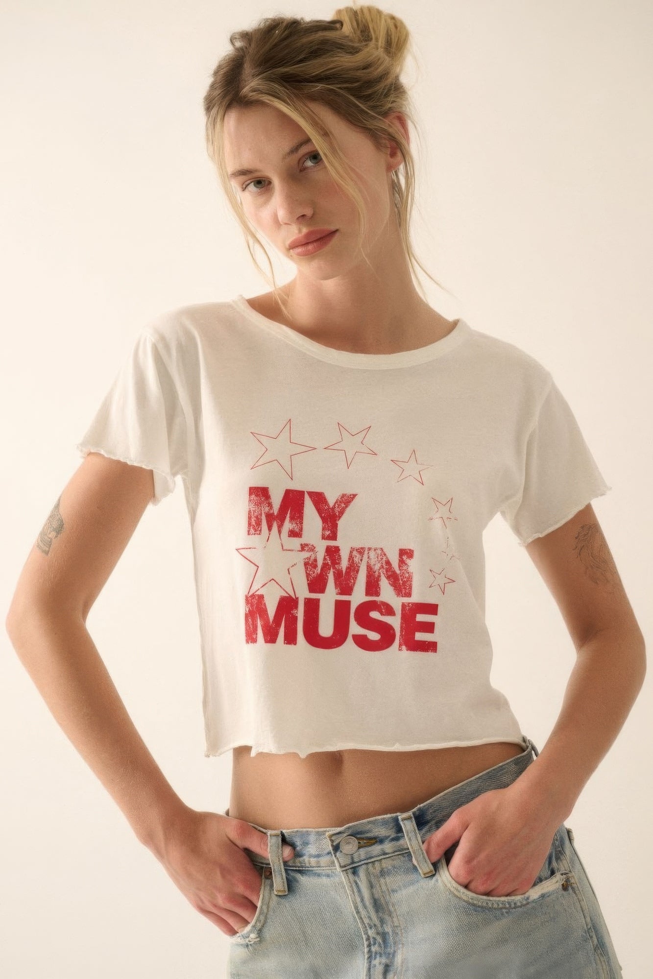 Woman wearing a My Own Muse vintage wash cropped graphic tee with star print in ivory, paired with high-waisted jeans.