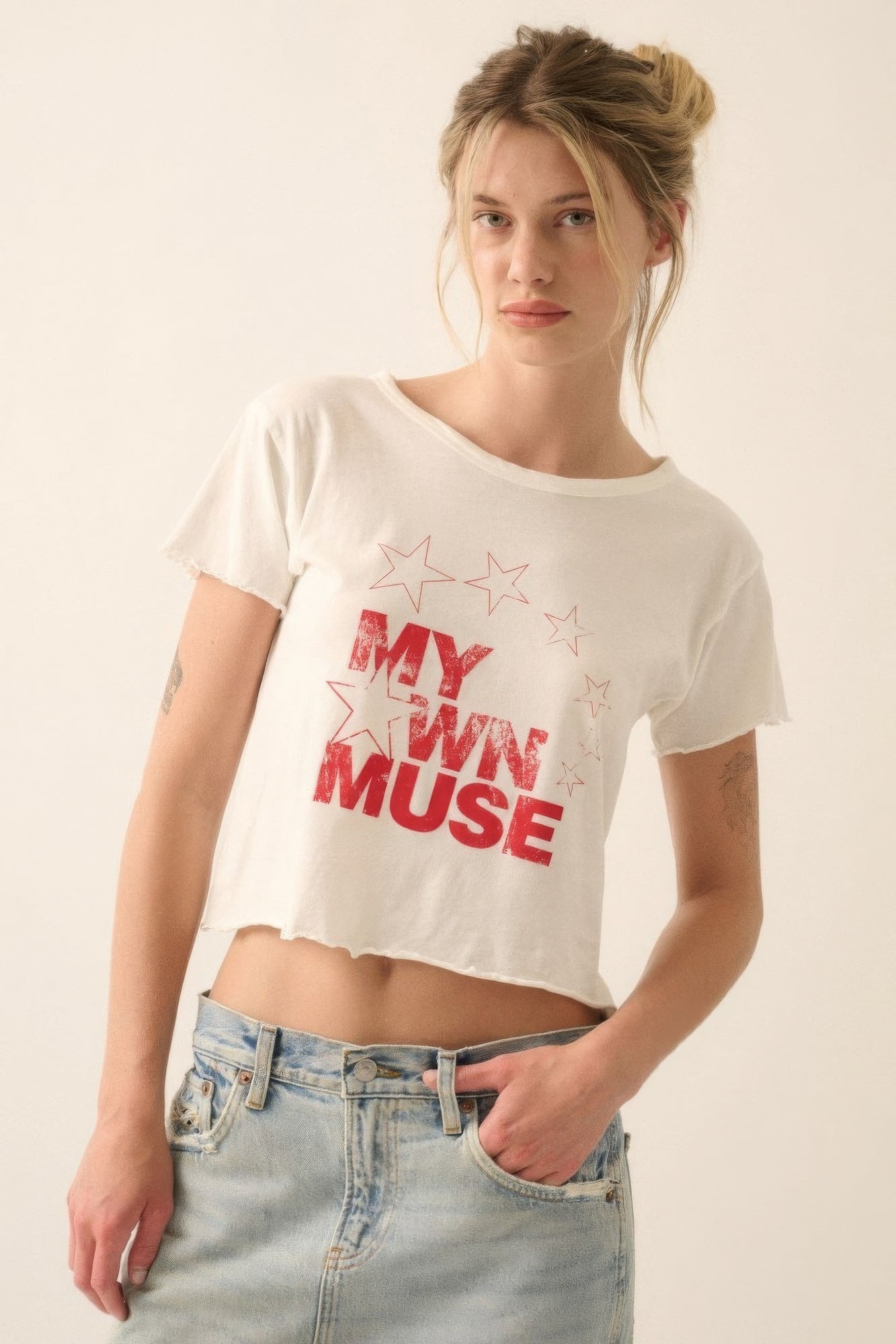 Woman wearing ivory "My Own Muse" vintage wash cropped tee with star print, styled with light denim jeans.