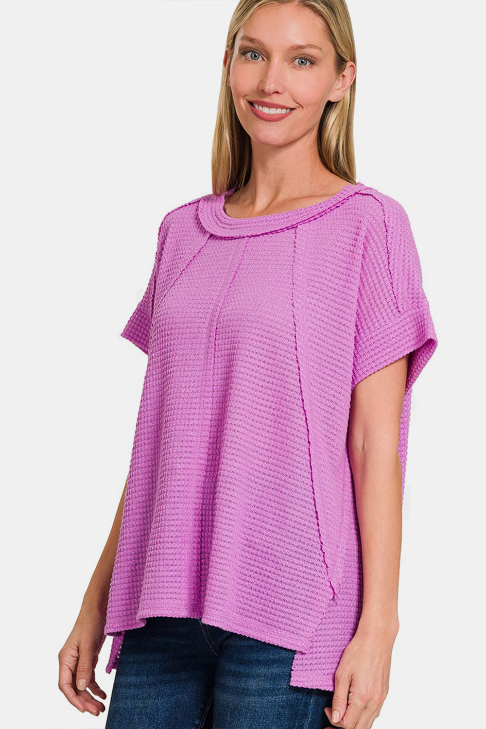 Woman wearing a purple waffle-knit exposed-seam short sleeve T-shirt made of polyester, rayon, and spandex.