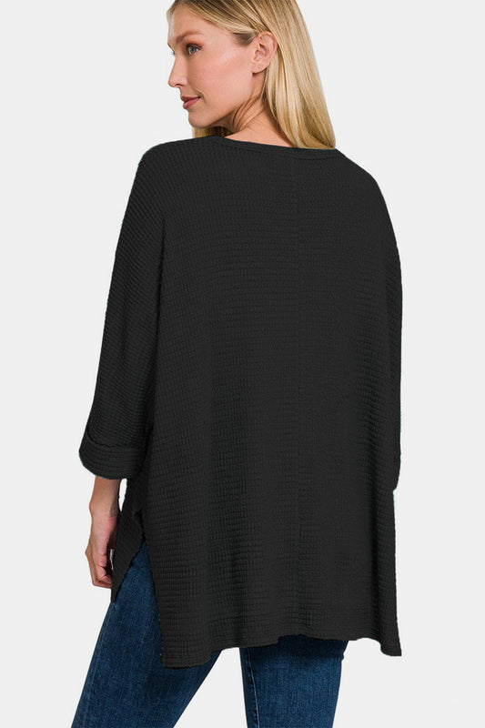 Woman wearing black waffle knit V-neck long sleeve slit top from back view.