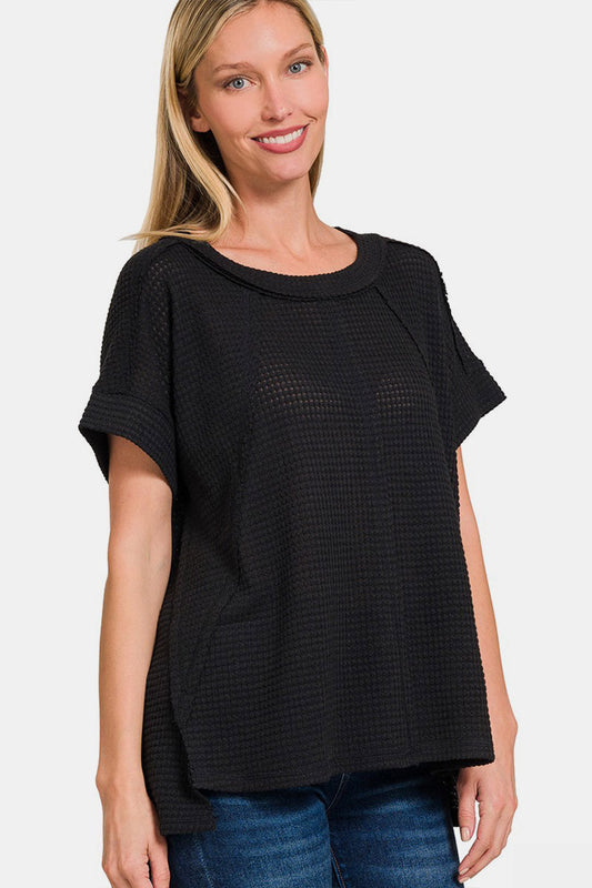 Woman wearing black waffle exposed-seam short sleeve t-shirt with trendy texture, paired with blue jeans for a casual look.