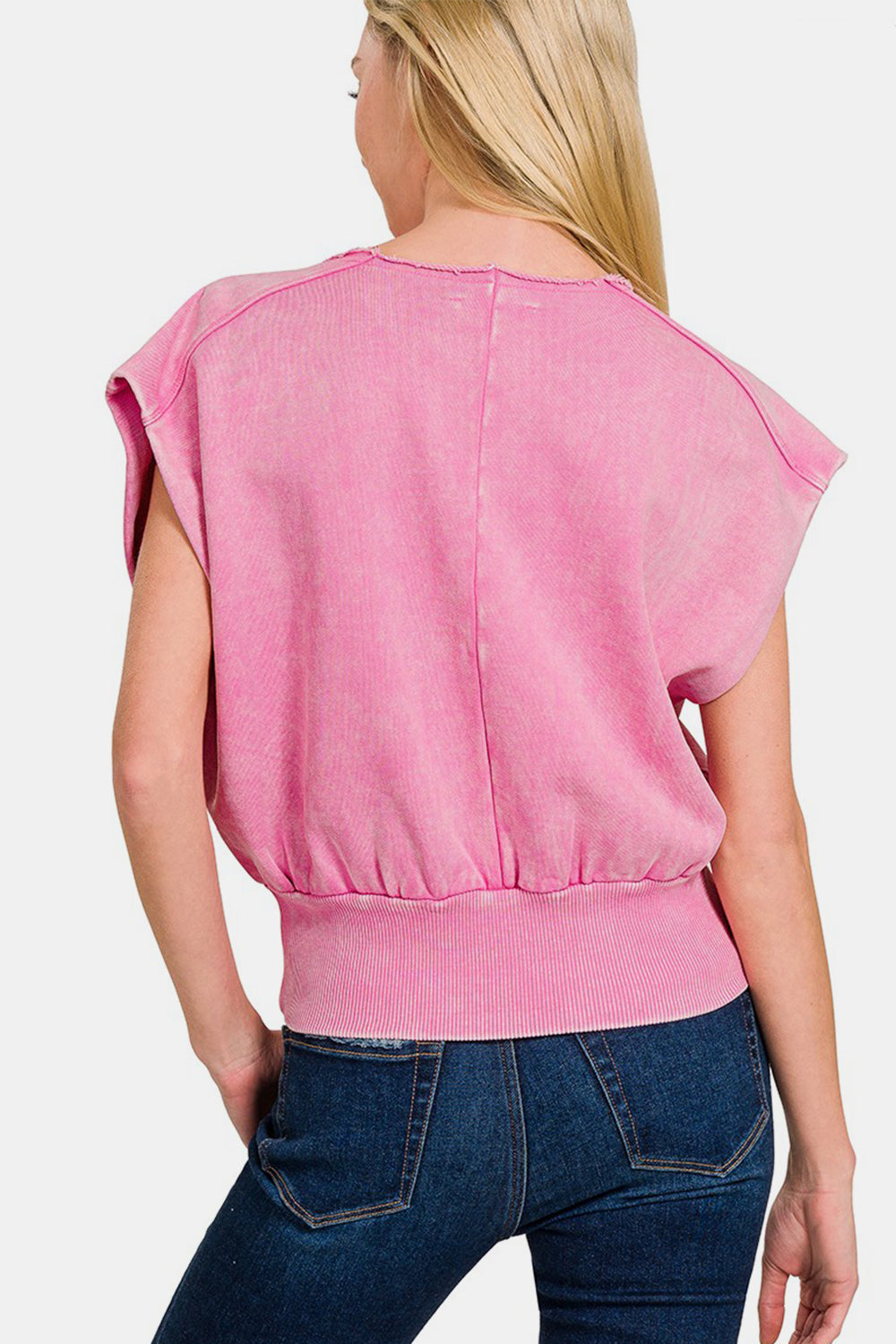 Woman wearing pink washed boat neck top with bottom band and dolman sleeves, paired with jeans, showcasing the back view.