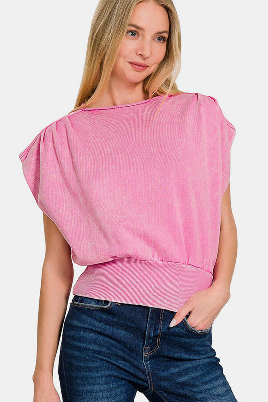 Woman wearing a pink washed boat neck top with dolman sleeves and a banded bottom, made of 100% cotton, styled casually with jeans.