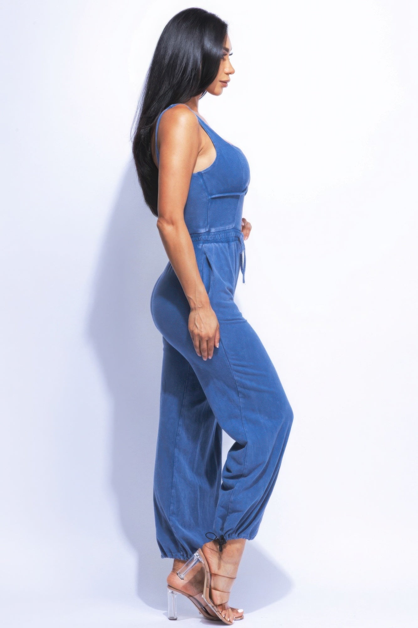 Woman wearing washed denim jumpsuit with adjustable ankle ties, showcasing a chic, relaxed fit and vintage-inspired look.