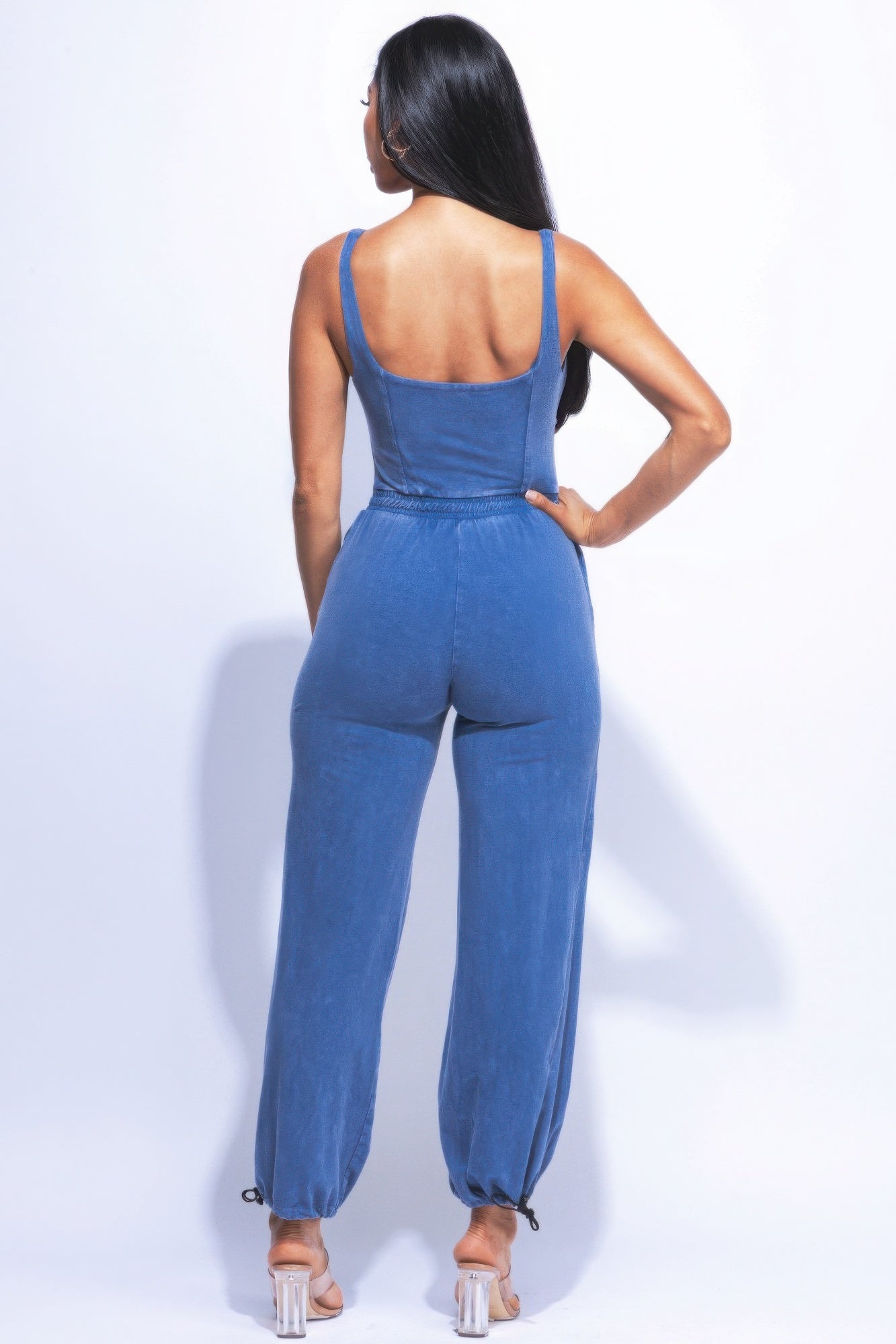 Woman wearing washed denim jumpsuit with adjustable ankle ties, showcasing relaxed fit and vintage-inspired style.