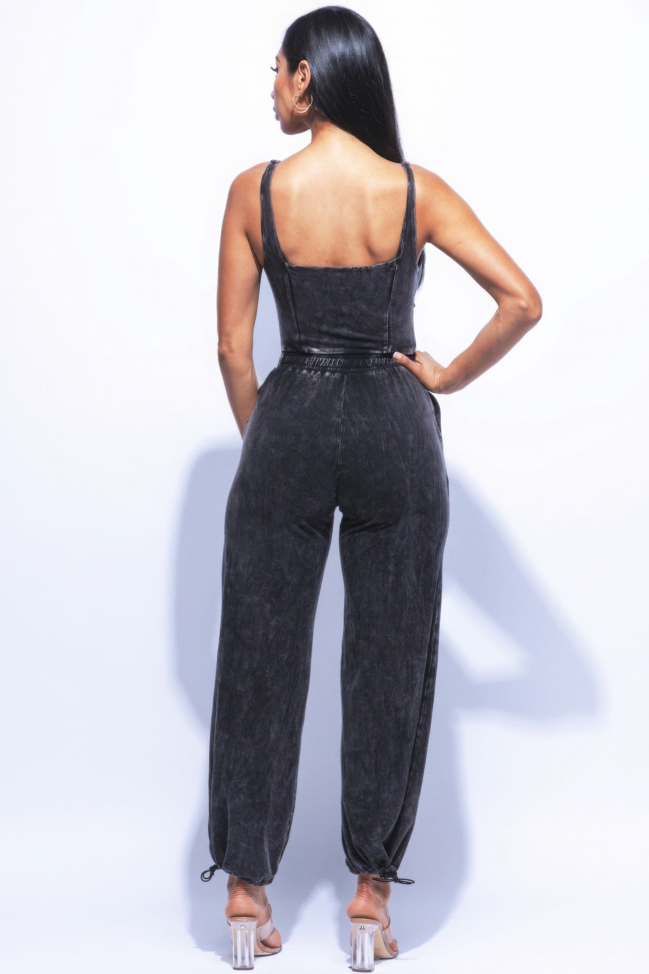 Woman wearing a washed denim jumpsuit with adjustable ankles, showcasing a relaxed fit and vintage-inspired style.