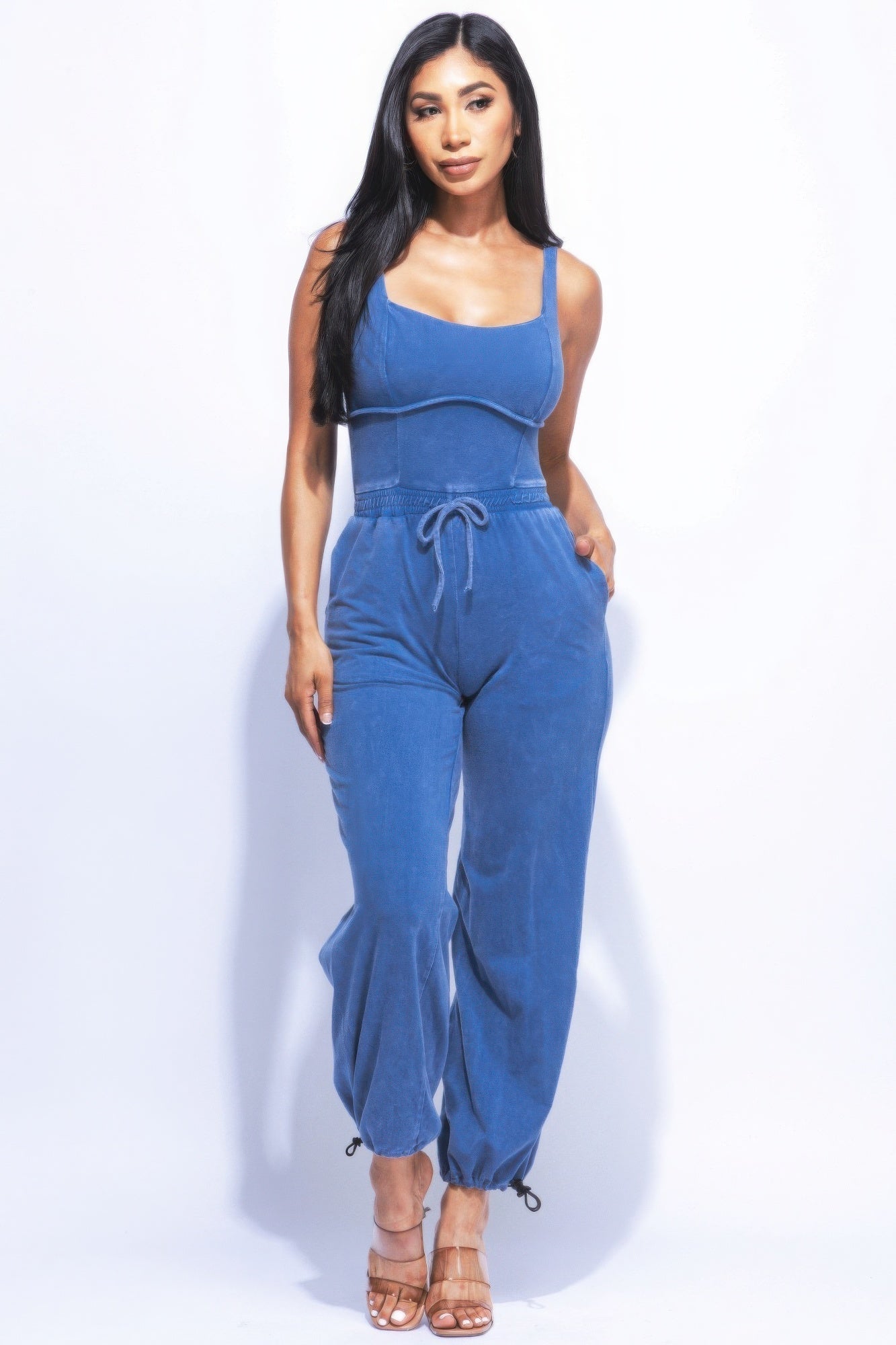 Woman wearing a blue washed denim jumpsuit with adjustable ankle ties, showcasing a chic and relaxed fit for versatile style.