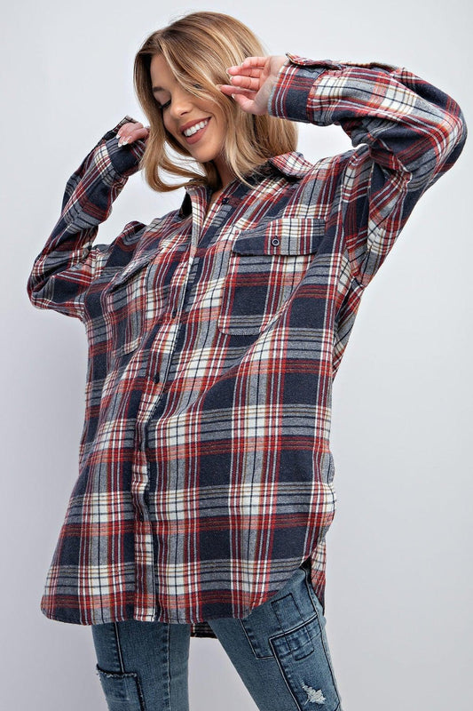 Woman wearing a relaxed plaid button-down shirt with collared neckline and flap pockets.