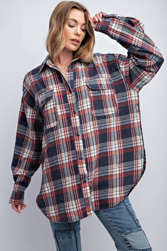 Woman wearing a relaxed fit washed plaid button-down shirt with flap pockets and rounded hem.