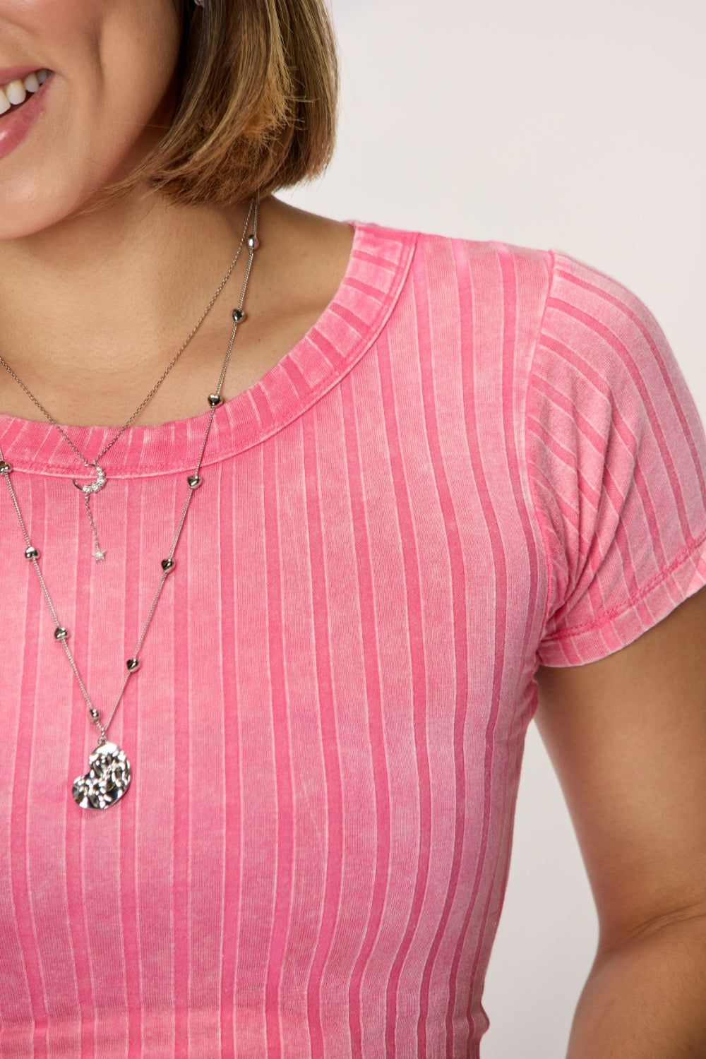 Pink washed ribbed short sleeve cropped t-shirt featuring a highly stretchy rayon and spandex blend, worn with a stylish necklace.