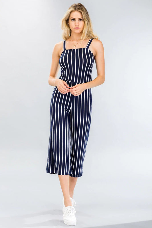 Woman wearing a striped wide-leg capri jumpsuit, sleeveless with a stretch knit fabric and allover stripe pattern.