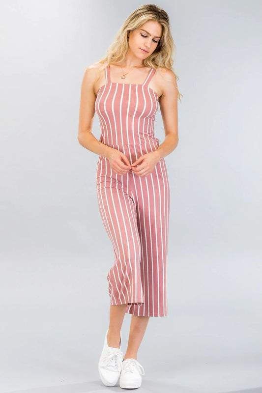 Woman wearing a sleeveless striped wide-leg capri jumpsuit in pink and white, with a stretch knit fabric and cami design.