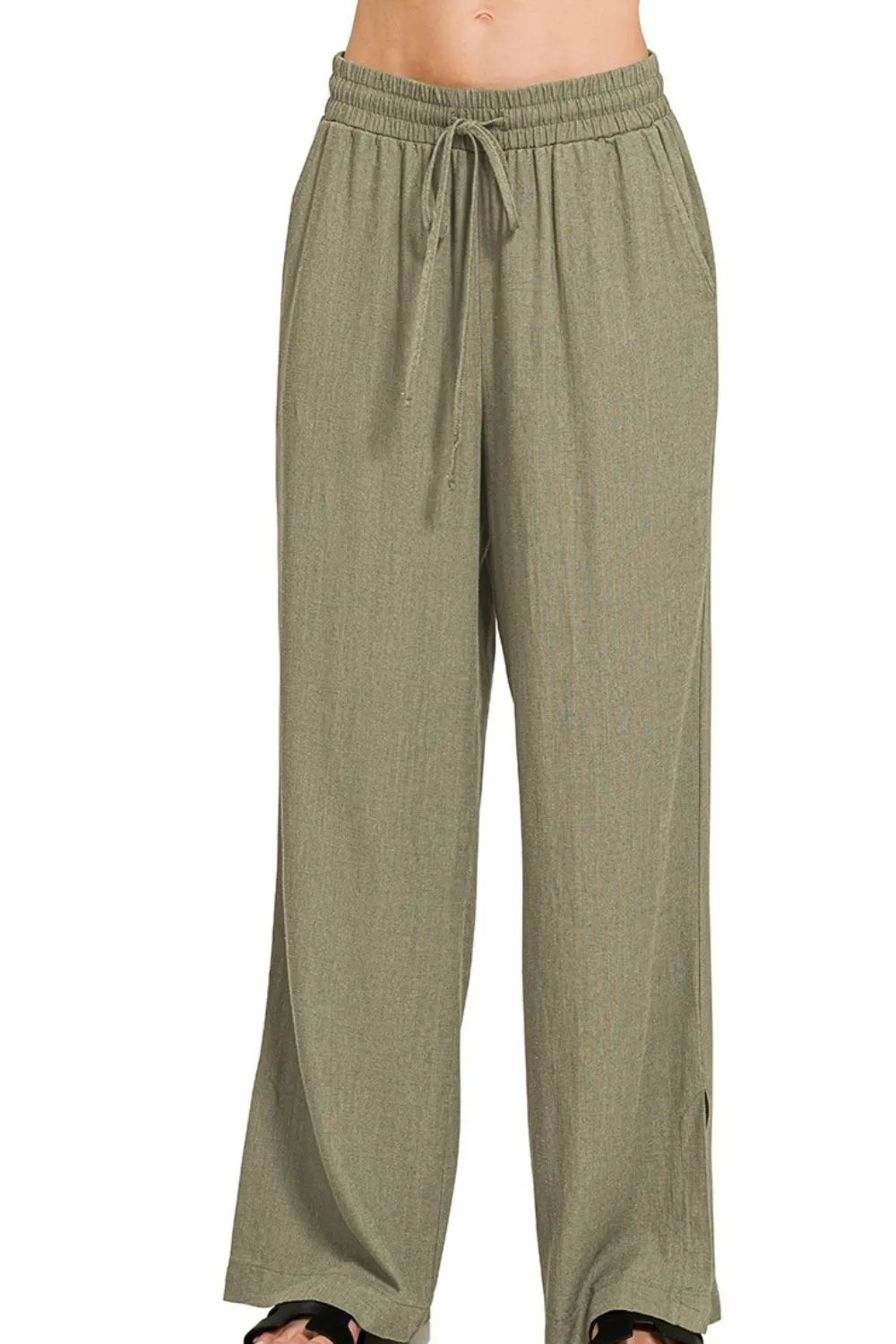 Woman wearing olive green wide-leg drawstring pants with elastic waistband, shown from waist down against white background.