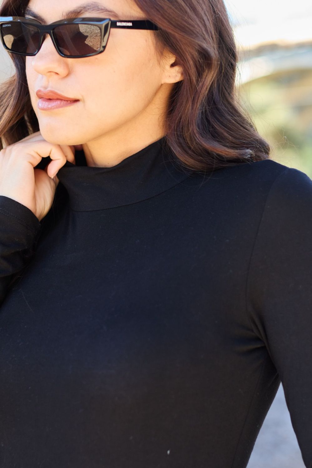 Woman wearing Basic Bae black mock neck long sleeve bodysuit and sunglasses outdoors.