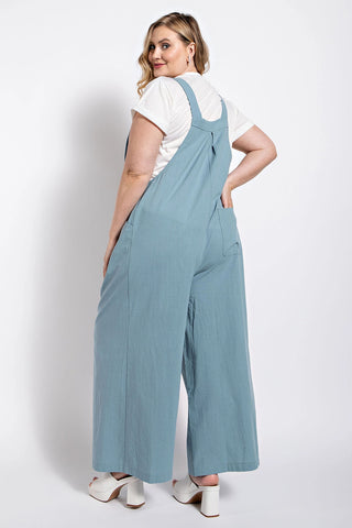 Woman wearing stone-colored pintuck detail overall with side pockets, crafted from soft cotton.
