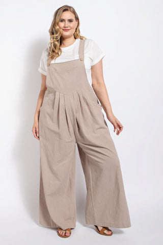 Woman in stone-colored pintuck detail overall with side pockets, showcasing casual elegance in comfortable cotton fabric.