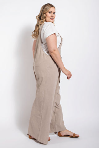 Woman wearing stone-colored pintuck detail overall with side pockets, crafted from soft cotton for casual elegance.