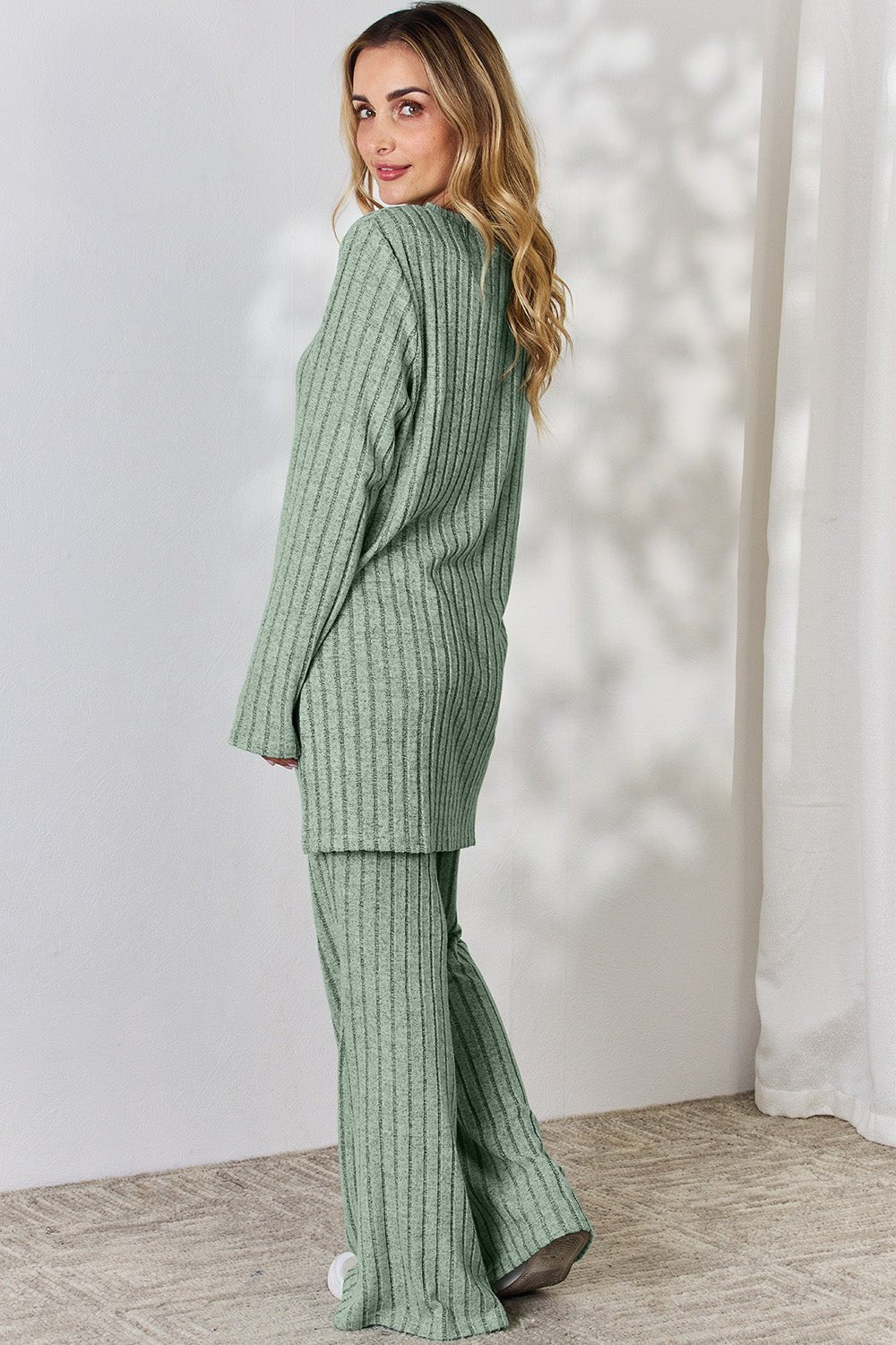 Woman wearing green ribbed high-low top and wide leg pants set, stylish two-piece with slightly stretchy material.