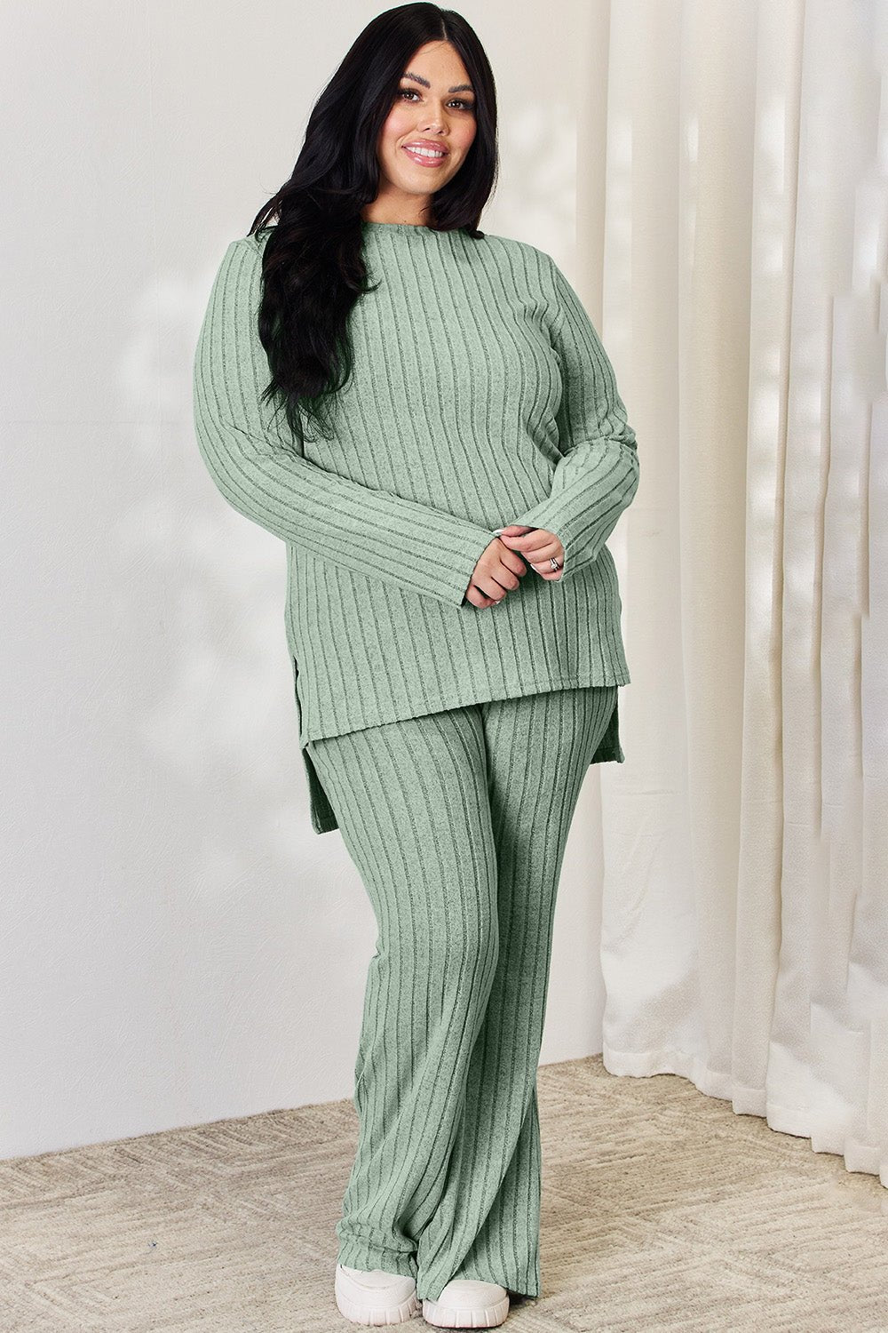 Curve model wearing green ribbed high-low top and wide-leg pants set, showcasing slightly stretchy material.