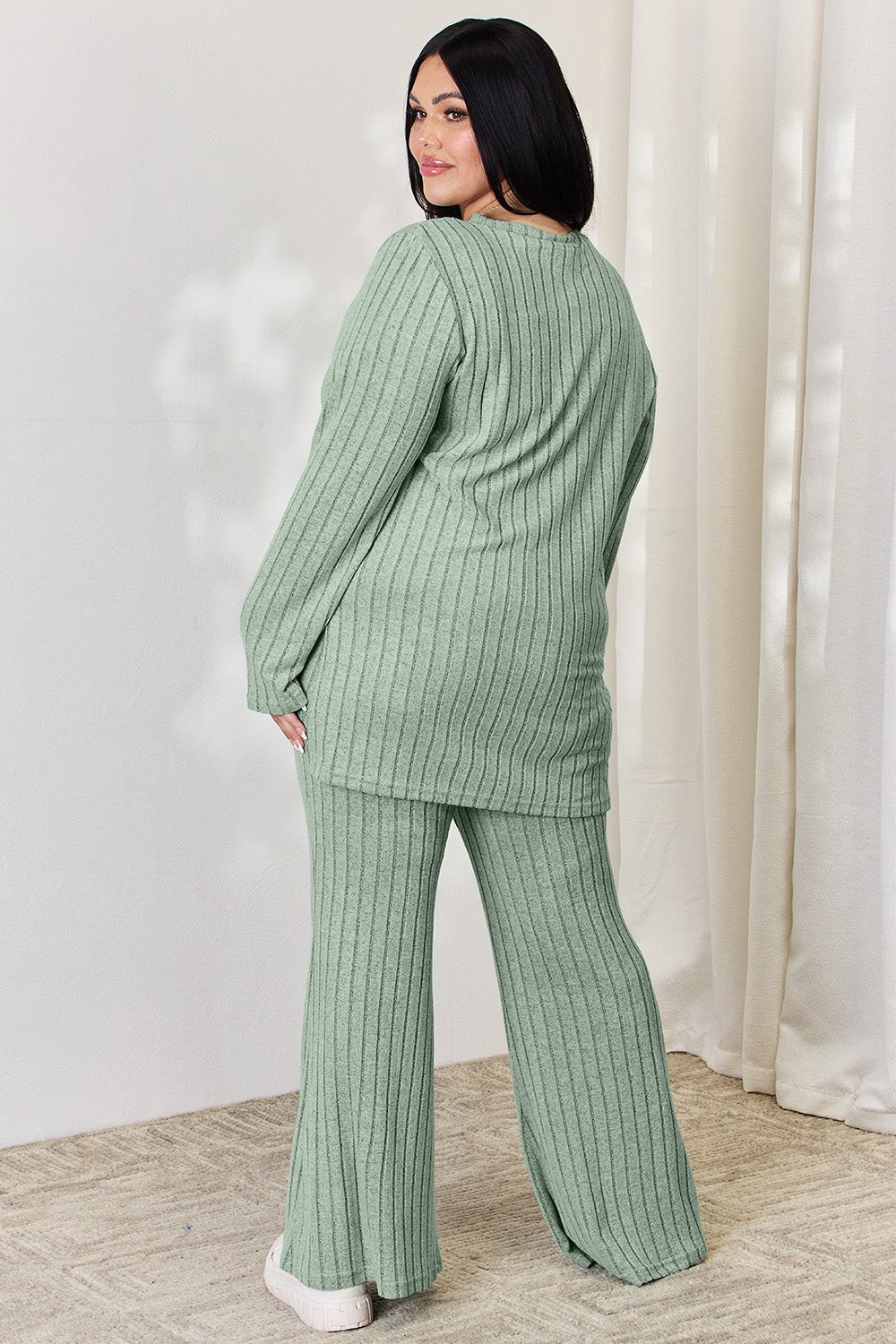 Woman in green ribbed high-low top and wide leg pants set, showing back view. Comfortable, stylish two-piece outfit.