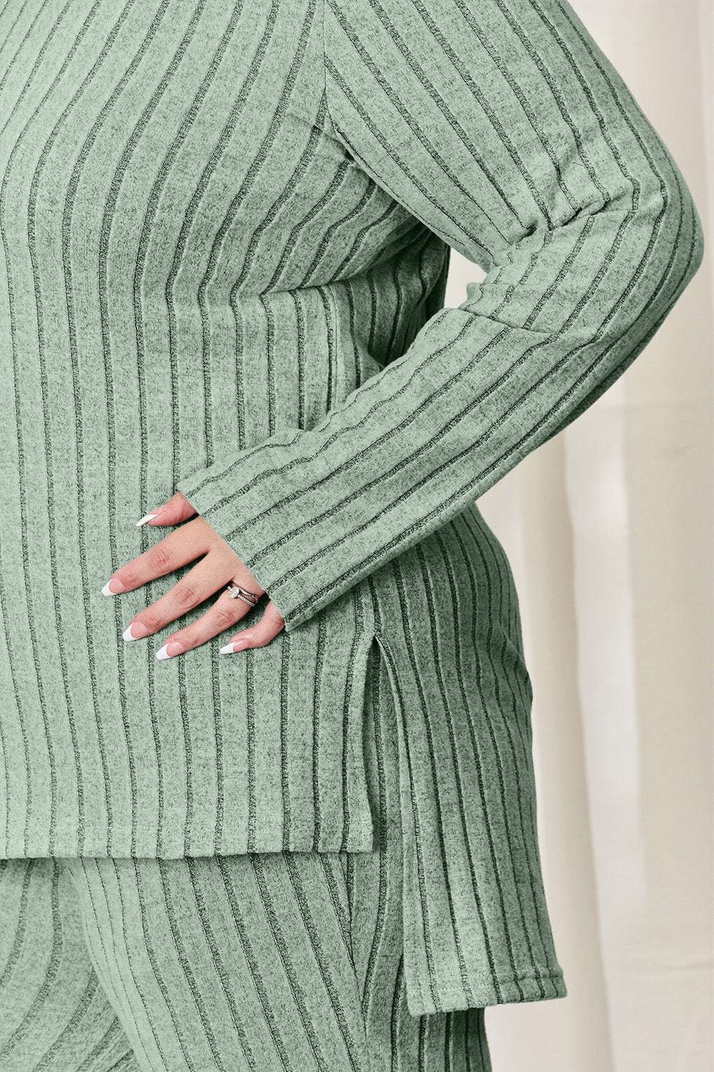 Ribbed high-low top and wide leg pants set in green, featuring a side slit and long sleeves, made of polyester and elastane mix.