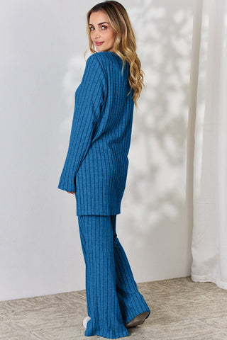 Woman wearing blue ribbed high-low top and wide leg pants set, showcasing back view in a stylish pose.
