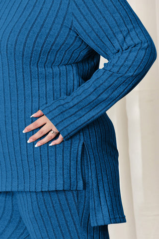 Plus size model wearing blue ribbed high-low top and wide-leg pants set, showcasing sleeve and side detail.