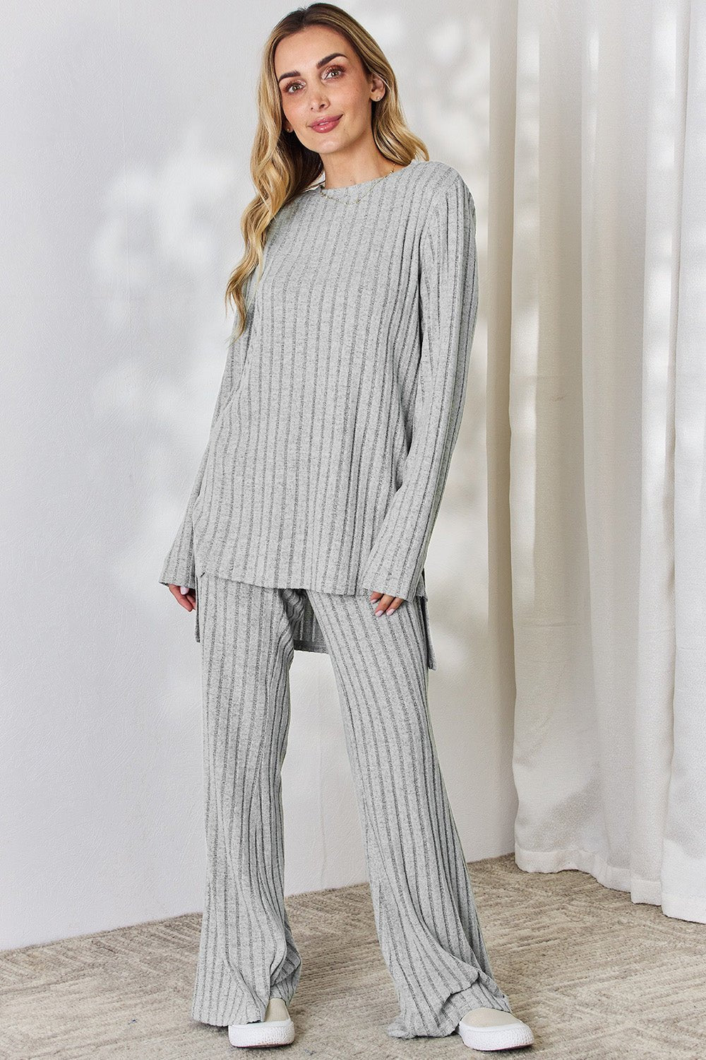 Woman wearing a gray ribbed high-low top and wide leg pants set, styled with sneakers, perfect for a casual look.