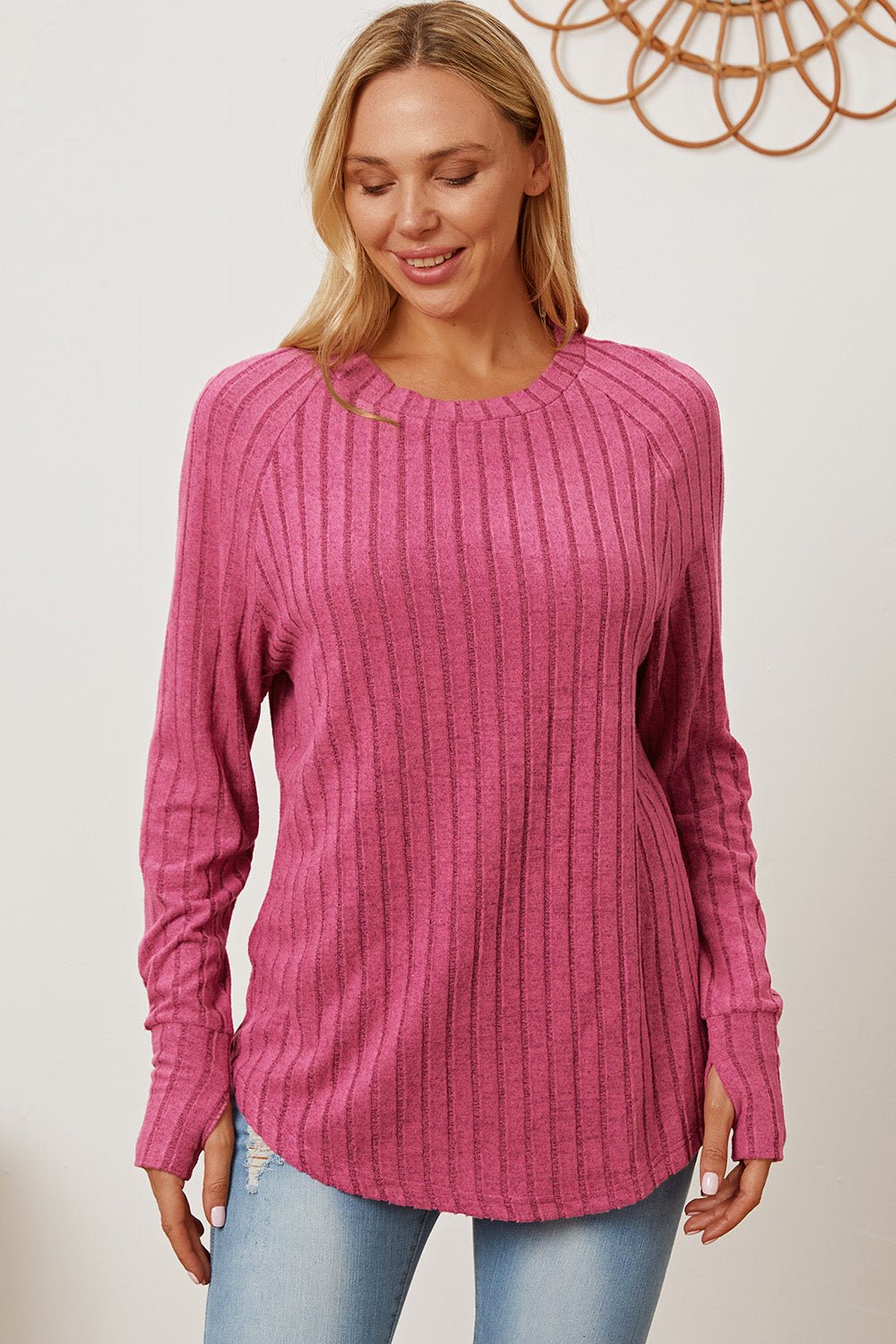 Woman wearing pink Basic Bae ribbed thumbhole sleeve t-shirt, paired with light jeans, smiling.