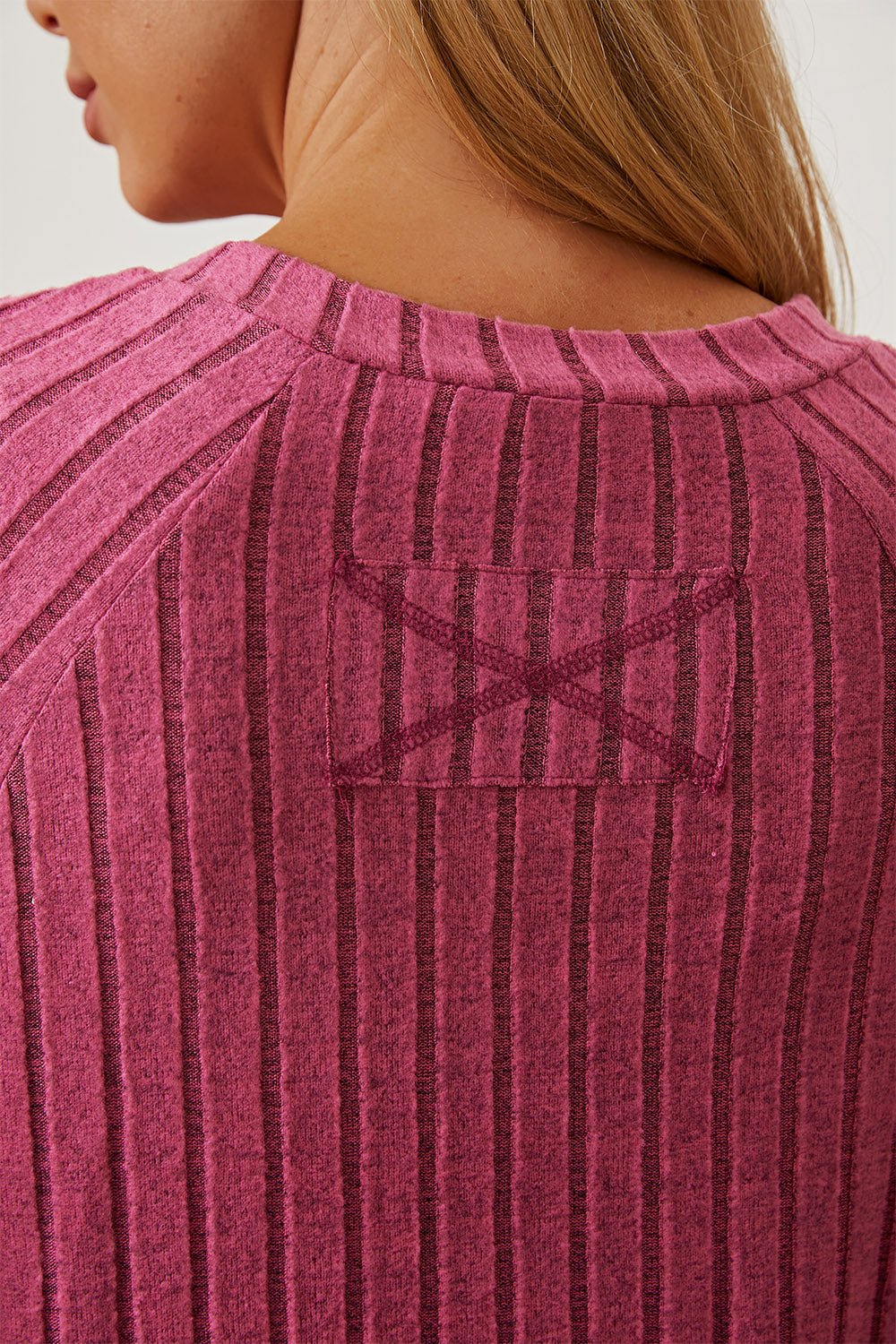 Close-up of ribbed fabric on a pink t-shirt showcasing detailed stitching and texture.